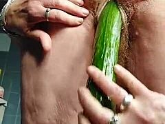 Nemška babica jebe dlakavo pičko s kumaro.